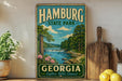 A vintage-style sign for Hamburg State Park in Georgia, featuring a scenic landscape with a river, trees, and flowers.