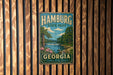 A vintage-style metal sign for Hamburg State Park in Georgia, featuring a scenic landscape with a river, trees, and a waterfall.