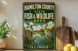 A vintage-style sign for the Hamilton County State Fish and Wildlife Area in Illinois, featuring illustrations of ducks, a heron, and a fish in a river setting.