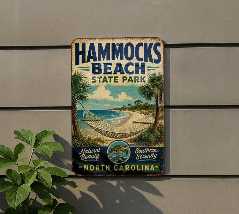 A vintage-style sign for Hammocks Beach State Park in North Carolina, featuring a beach scene with palm trees and a hammock.