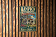 A vintage metal sign for the Hampton Plantation State Historic Site in South Carolina, featuring a house surrounded by palm trees and a blue sky.