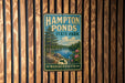 A vintage metal sign for Hampton Ponds State Park in Massachusetts, featuring a scenic landscape with a lake, pine trees, and a blue sky with clouds.
