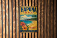 A vintage metal sign for Hapuna Beach, Hawaii, featuring a tropical beach scene with palm trees and flowers.