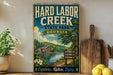 a vintage-style metal sign for Hard Labor Creek State Park in Georgia, with a scenic illustration of a lake, mountains, and a cabin. The sign encourages visitors to explore, relax, and enjoy the natural beauty of the park.