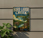 A vintage-style metal sign for Hard Labor Creek State Park in Georgia, featuring a scenic landscape with a lake, mountains, and a cabin.