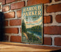 A vintage-style metal sign for the Harold Parker State Forest in Massachusetts, featuring a scenic landscape with a river and pine trees.