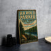 A vintage-style metal sign for Harold Parker State Forest in Massachusetts, featuring a scenic illustration of a forest and a lake.