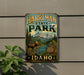 A vintage metal sign for Harriman State Park in Idaho, featuring a moose and a mountain landscape.
