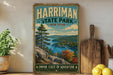 A vintage-style sign for Harriman State Park in New York, featuring a scenic landscape with a lake and mountains.