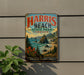 A vintage-style metal sign for the coastal park, featuring a scenic landscape with mountains, trees, and a beach.