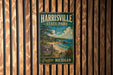 A vintage metal sign for Harrisville State Park in Michigan, featuring a scenic landscape with a lake, forest, and beach.