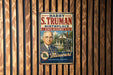 A vintage metal sign featuring a portrait of a man with the text "Harry S. Truman Birthplace State Historic Site" and "I WAS BORN IN A LITTLE HOUSE, MISSOURI" displayed on a wooden wall.