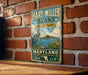 A vintage metal sign for Hart-Miller Island State Park in Maryland, featuring a blue heron and a scenic landscape.