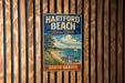 A vintage metal sign for Hartford Beach State Park in South Dakota, featuring a scenic illustration of the beach and surrounding landscape.