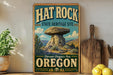 A vintage-style metal sign for the Hat Rock State Heritage Site in Oregon, featuring a large mushroom-shaped rock formation and the text "Discover Oregon's Past" and "Oregon".
