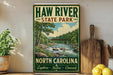 A vintage-style metal sign for Haw River State Park in North Carolina, featuring a scenic illustration of a river and forest landscape.