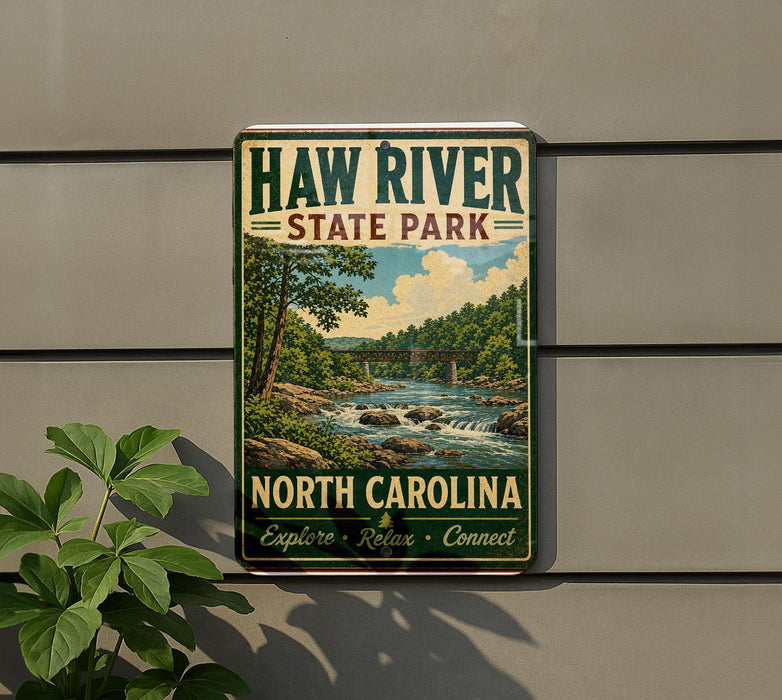 A vintage-style metal sign for Haw River State Park in North Carolina, featuring a scenic landscape with a river, trees, and a bridge.