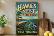 A vintage-style sign for Hawk's Nest State Park in West Virginia, featuring a scenic mountain landscape with a river and pine trees.
