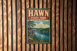 A vintage-style metal sign for Hawn State Park in Missouri, featuring a scenic landscape with a lake, mountains, and a cliff.