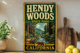 A vintage-style sign for Hendy Woods State Park in California, featuring a scenic illustration of a forest and a river.