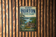 A vintage-style metal sign for Henry Horton State Park in Tennessee, featuring a scenic landscape with a lake and mountains.