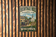 A vintage metal sign for Heritage Hill State Historical Park in Wisconsin, featuring an illustration of a historic building and a horse-drawn carriage.