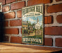 A vintage-style metal sign for Heritage Hill State Historical Park in Wisconsin, featuring an illustration of a historic building and a horse-drawn carriage.