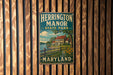 A vintage metal sign for Herrington Manor State Park in Maryland, featuring a house and a river, is displayed on a wooden wall.