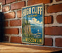 A vintage-style metal sign for High Cliff State Park in Wisconsin, featuring a scenic image of the park's cliffs and water.