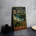 A vintage-style metal sign for Historic Blakeley State Park in Alabama, featuring a cannon and a tree, is displayed on a gray countertop.