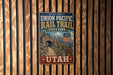 A vintage-style metal sign for the Union Pacific Rail Trail in Utah, featuring a scenic image of a tunnel and mountains.