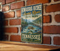 A vintage-style sign for Hiwasseeochee Scenic River State Park in Tennessee, featuring a river scene with people rafting.