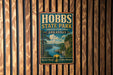 A vintage metal sign for Hobbs State Park, featuring a scenic landscape with a river and mountains, mounted on a wooden wall.