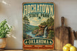 A vintage-style sign for HochatOWN State Park in Oklahoma, featuring a scenic landscape with a waterfall and pine trees.