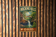 A vintage-style metal sign for Hocking Hills State Park in Ohio, featuring a scenic image of a waterfall surrounded by lush greenery.
