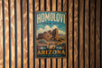 A vintage metal sign for Homolovi State Park in Arizona, featuring an illustration of a desert landscape with a large pottery structure.