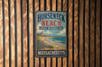 A vintage metal sign for Horseneck Beach, Massachusetts, featuring a lighthouse and beach scene.