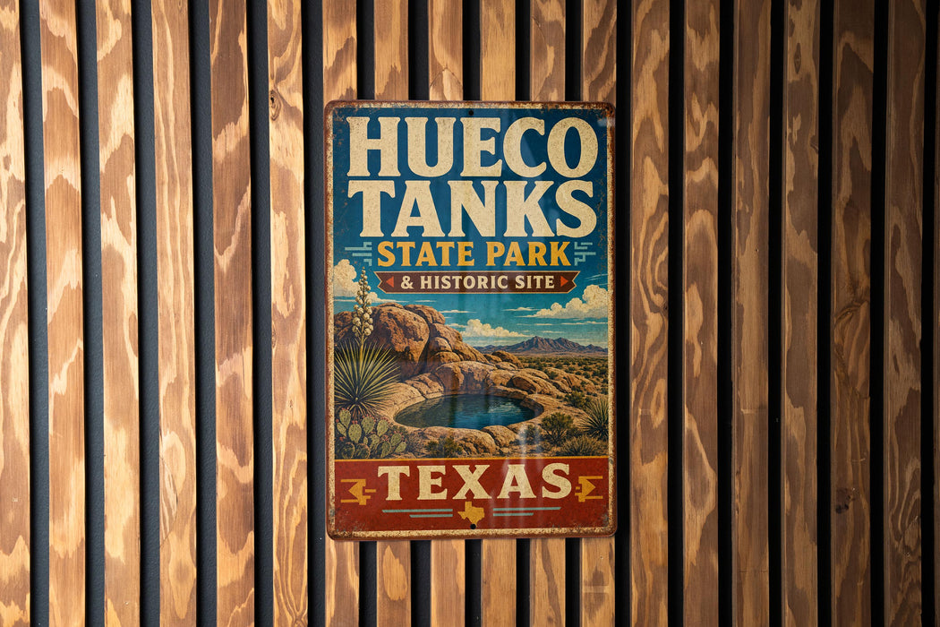 A vintage-style metal sign for Hueco Tanks State Park & Historic Site in Texas, featuring a desert landscape with a cactus and a small pool.
