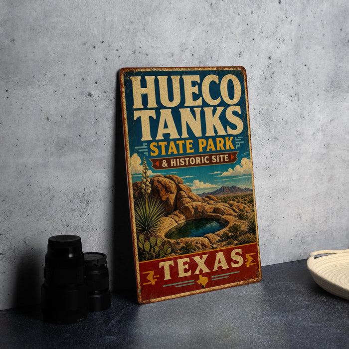 A vintage-style sign for Hueco Tanks State Park & Historic Site in Texas, featuring a desert landscape with a lake and cacti.