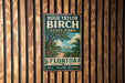 A vintage-style metal sign for Hugh Taylor Birch State Park in Florida, featuring a tropical landscape with palm trees and a body of water.