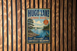 A vintage-style sign for Hugo Lake State Park, featuring a scenic illustration of a lake, trees, and a boat, mounted on a wooden wall.