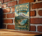 A vintage metal sign for Humbug Mountain State Park in Oregon, featuring a scenic mountain landscape and the text "Oregon Explore, Relax, Enjoy."