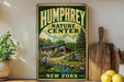 A vintage-style metal sign for the Humfrey Nature Center in New York, featuring an illustration of a pond, a bird, and a wooden cabin surrounded by trees.