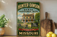 A vintage-style sign for the Hunter-Dawson State Historic Site in Missouri, featuring a house and a wooden sign with text.