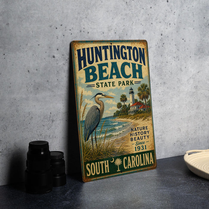 A vintage metal sign for Huntington Beach State Park, featuring a bird and a lighthouse, is displayed on a table.