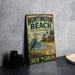 A vintage metal sign for Huntington Beach State Park, featuring a bird and a lighthouse, is displayed on a table.