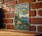 A vintage-style sign for "HUNTS POINT RIVERSIDE AID" is displayed on a brick wall, with a wooden table below it.
