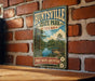 A vintage-style metal sign for the "Piney Woods Adventure" in Huntsville, Texas, featuring a scenic landscape with a lake and a wooden dock.