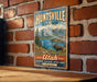 A vintage metal sign for Huntsville State Park, featuring a moose and a scenic mountain landscape.