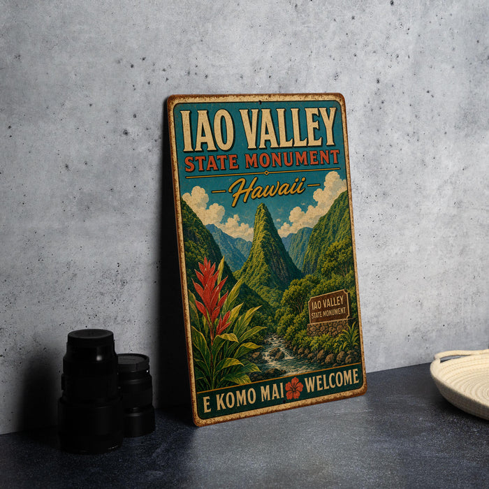 A vintage-style metal sign for the Iao Valley State Monument in Hawaii, featuring a mountainous landscape with a waterfall and tropical flora.